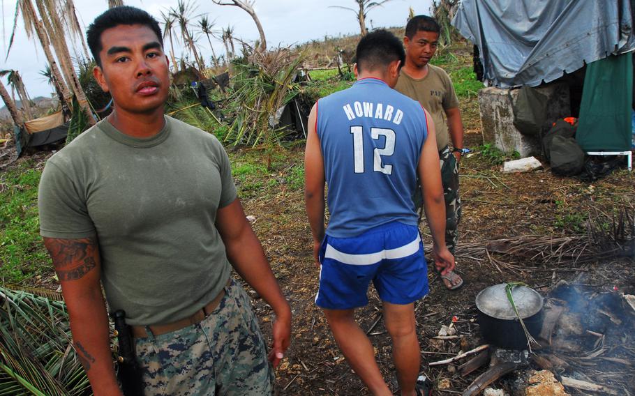 U.S. Marine Staff Sgt. John Suyat, 32, of Alexandria, Va., left, hung out with Filipino airmen while they cooked a local dinner on Thursday, Nov. 21, 2013, during typhoon relief operations in The Philippines.