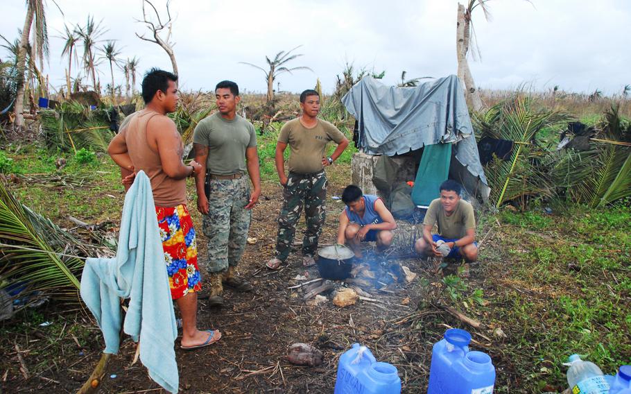 U.S. Marine Staff Sgt. John Suyat, 32, of Alexandria, Va., second from left, hung out with Filipino airmen while they cooked a local dinner on Thursday, Nov. 21, 2013, during typhoon relief operations in the Philippines.