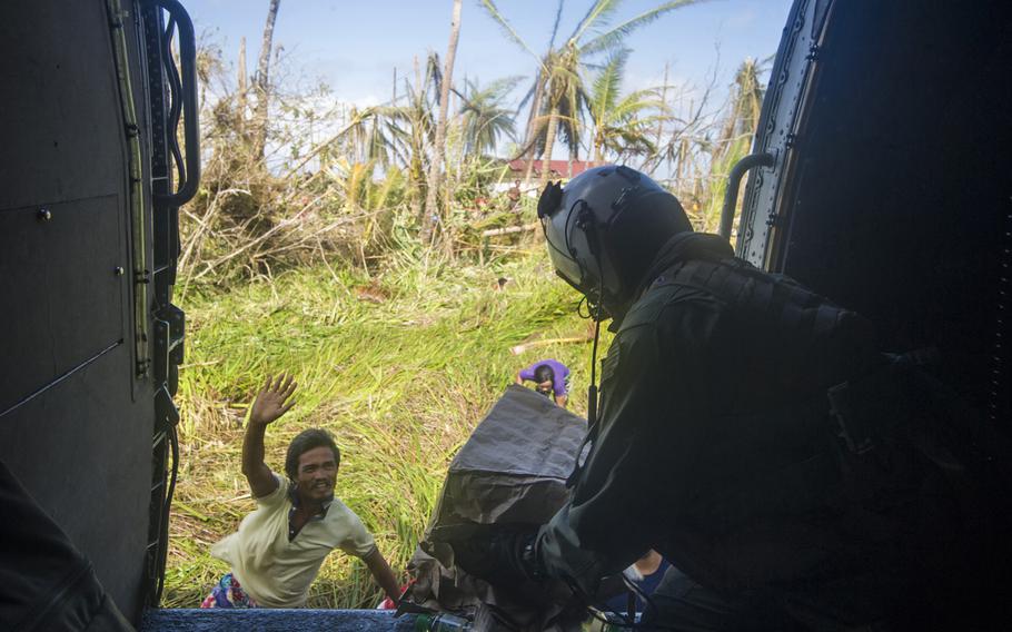 Petty Officer 3rd Class Peter Olson distributes supplies from an SH-60B Seahawk to citizens on Leyte in support of Operation Damayan in The Philippines on Nov. 16, 2013. The Seahawk is assigned to guided-missile cruiser USS Cowpens. Aboard Cowpens are several Philippine-born U.S. sailors helping with the post-typhoon aid effort.