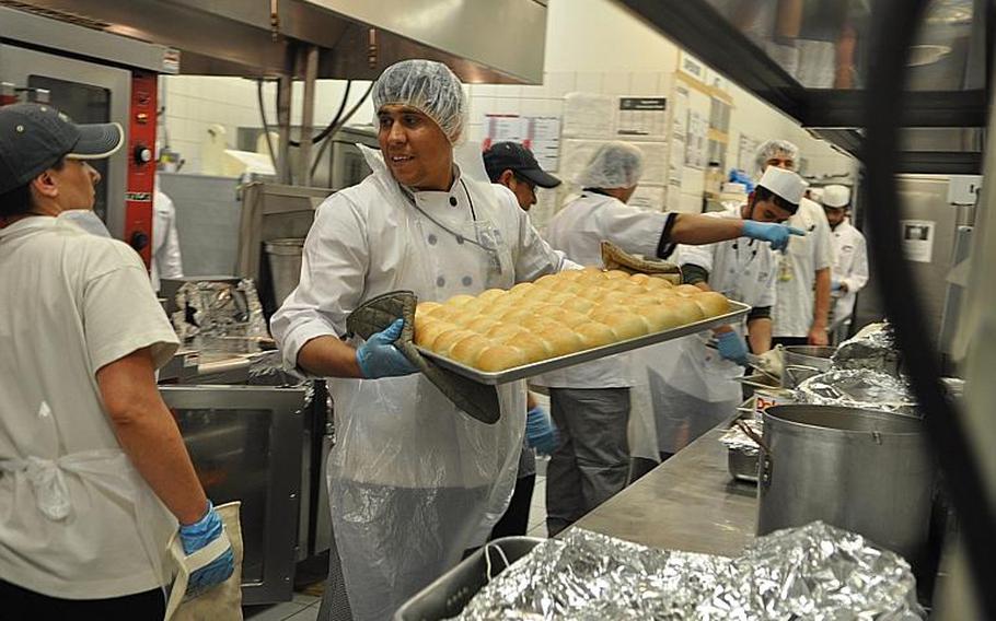An Afghan contractor, Khuja, carries a tray of freshly baked bread rolls. While New Kabul Compound has a relatively well equipped kitchen, many small Forward Operating Bases celebrated Thanksgiving with special pre-prepared Unitized Group Rations, which spokesman Jeff Hawk said included turkey, mashed potatoes, gravy, carrots, a "raisin-nut mix with chocolate discs," cranberry jelly and poultry seasoning, plus some special extras like eggnog and pie. 