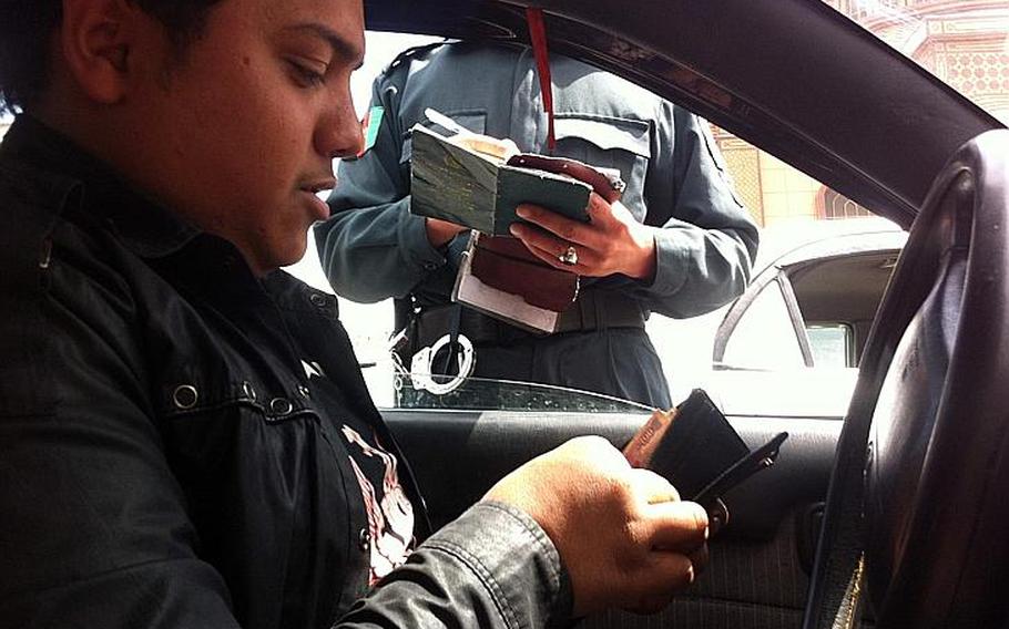 A taxi driver prepares to pay about $5 to a Kabul Traffic Police officer who had questioned the validity of his driver's license in this file photo from April 2013. The officer issued no tickets and slipped the money in his pocket. For the second year in a row, Afghanistan rounds out the bottom of Transparency International?s Corruption Perceptions index, tied with North Korea and Somalia.
