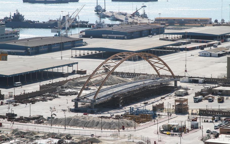 A tied-arch suspension bridge is being assembled across from Naval Support Activity Bahrain, Dec. 5, 2013. Next month the 2,500-ton bridge is scheduled to be lifted and moved into position over the roadway connecting the base to 77 acres of land the Navy leases along the waterfront.