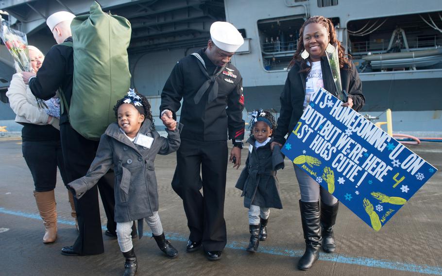 Petty Officer 1st Class Quindric Woods, center, from Baton Rouge, La., reunites with his family after the aircraft carrier USS Nimitz arrives at homeport at Naval Station Everett, Wash., on Dec. 16, 2013.