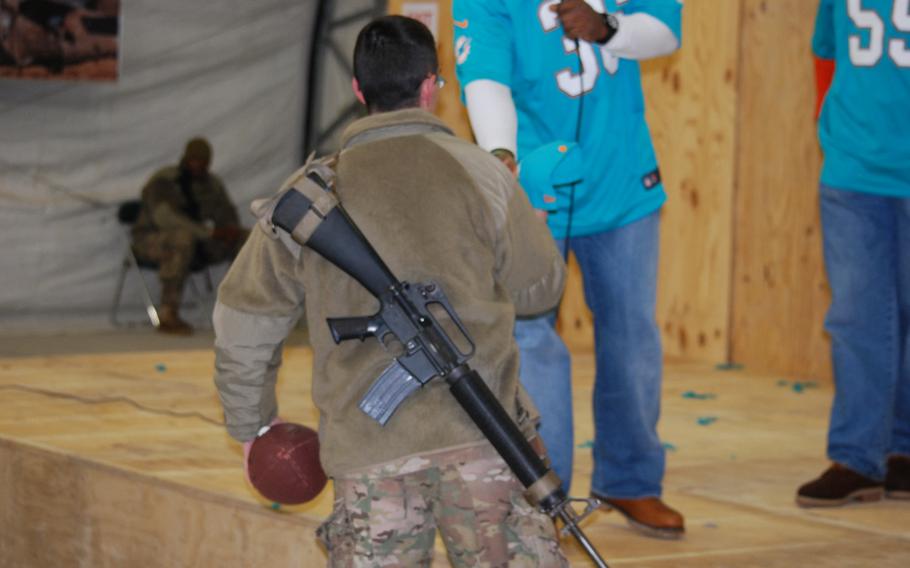 A U.S. soldier talks with former NFL players Derrick Rodgers and Lousaka Polite about the proper gripping of a football while running on Sunday, Feb. 2, 2014. The NFL players were on a tour of northern Afghanistan with the Armed Forces Entertainment agency.