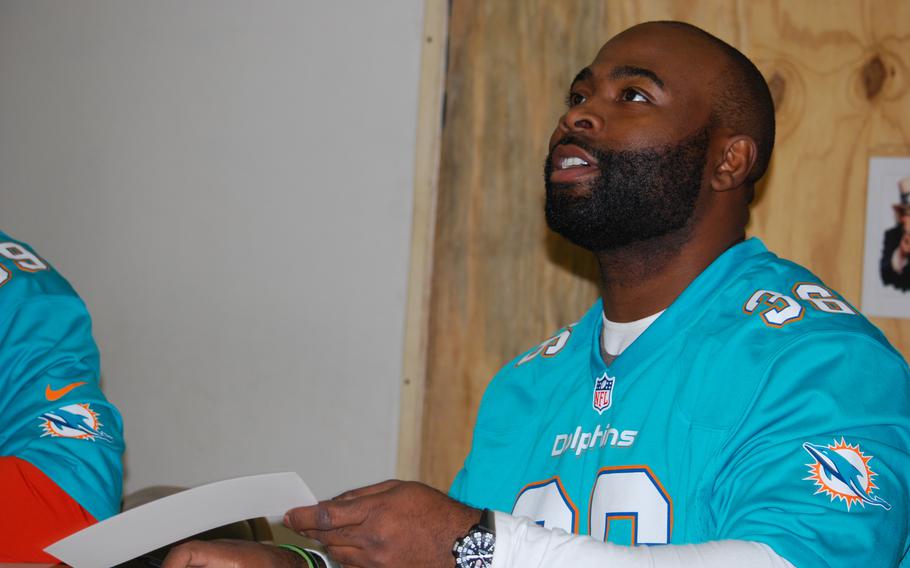 Lousaka Polite, former Miami Dolphins fullback, returns a signed card to a coalition servivemember at Camp Marmal in Mazar-e-Sharif, Afghanistan, on Super Bowl Sunday, Feb. 2, 2014. Polite was in Afghanistan on a tour of Regional Command North with the Armed Forces Entertainment agency.