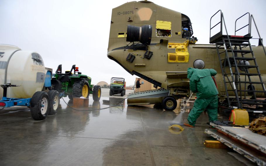 Hilario Veltran, a DynCorp employee, hoses down airplane parts under a light sprinkle of snow. When weather shut down most flight operations at Kandahar Air Field for a week in early February, it left time for crews to catch up on maintenance.