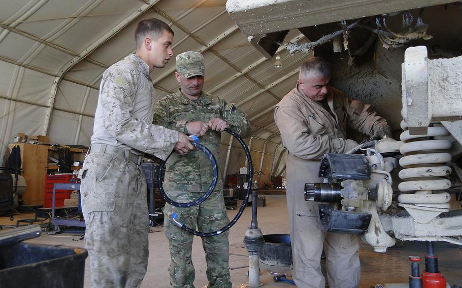Left to right, U.S. Marine Cpl. Parker Fletcher, interpreter Temur Okruashvili and Georgian Army mechanic Gocha Ushveridze work together to repair an MRAP in the Georgian vehicle maintenance shop at Camp Leatherneck. Six American mechanics and six Georgian mechanics work together in the shop.