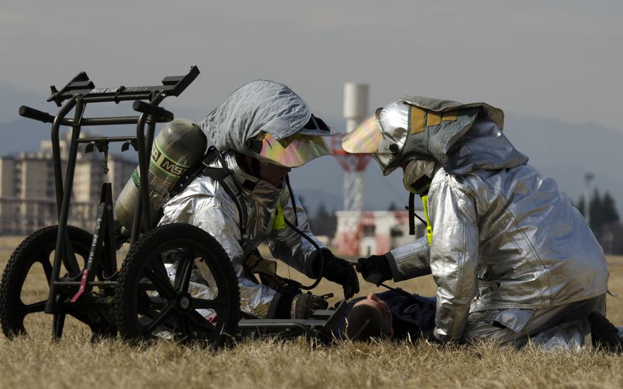 Two firemen from the Yokota Fire Department tend to the simulated injuries of an airman assigned to the 374th Airlift during the Samurai Readiness Insepction at Yokota Air Base March 3, 2014.