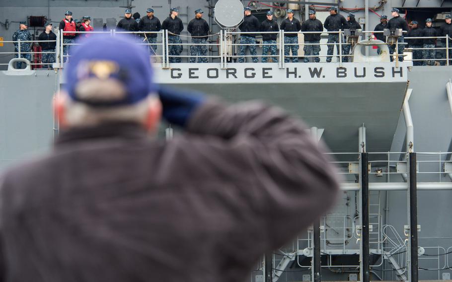 Retired Senior Chief Jim Newton salutes sailors aboard the aircraft carrier USS George H.W. Bush as the ship departs Naval Station Norfolk on Feb. 15, 2014, for a scheduled deployment.