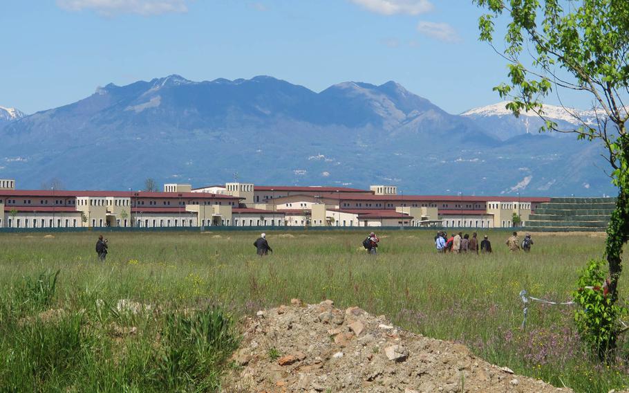 Italian journalists trek out to the site where a giant World War II-era bomb was found in a field next to the U.S. Army's Del Din base. It is to be defused and removed on April 25, 2014. 