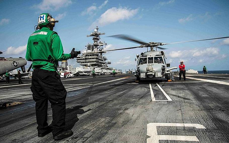 Seaman Kevin Grafton directs an MH-60R Seahawk taking off from the aircraft carrier USS George H.W. Bush in the Arabian Sea March 27, 2014. Grafton, assigned to Helicopter Maritime Strike Squadron 70, is from Dallas.