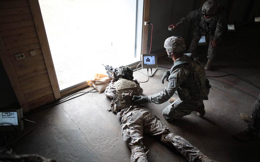After running a quarter mile in a gas mask and dragging a "casualty" hundreds of yards, a Latvian soldier fires a rifle at a target hundreds of yards away Wednesday, April 30, 2014, as part of a shooting exercise meant to simulate the stress of battlefield conditions and build teamwork between American and Latvian soldiers.