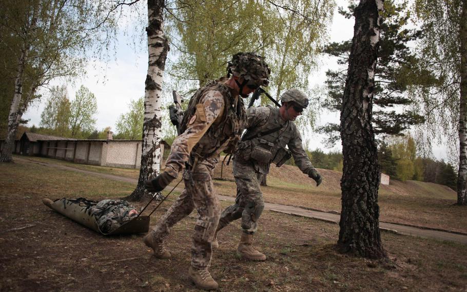 A Latvian and an American soldier drag a "casualty" Wednesday, April 30, 2014, during a shooting exercise designed to build camaraderie between the soldiers while putting them under extreme stress to simulate battlefield conditions.