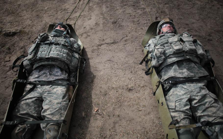 A pair of American soldiers wait to be dragged as "casualties" Wednesday, April 30, 2014, during a team-building exercise with Latvian soldiers.