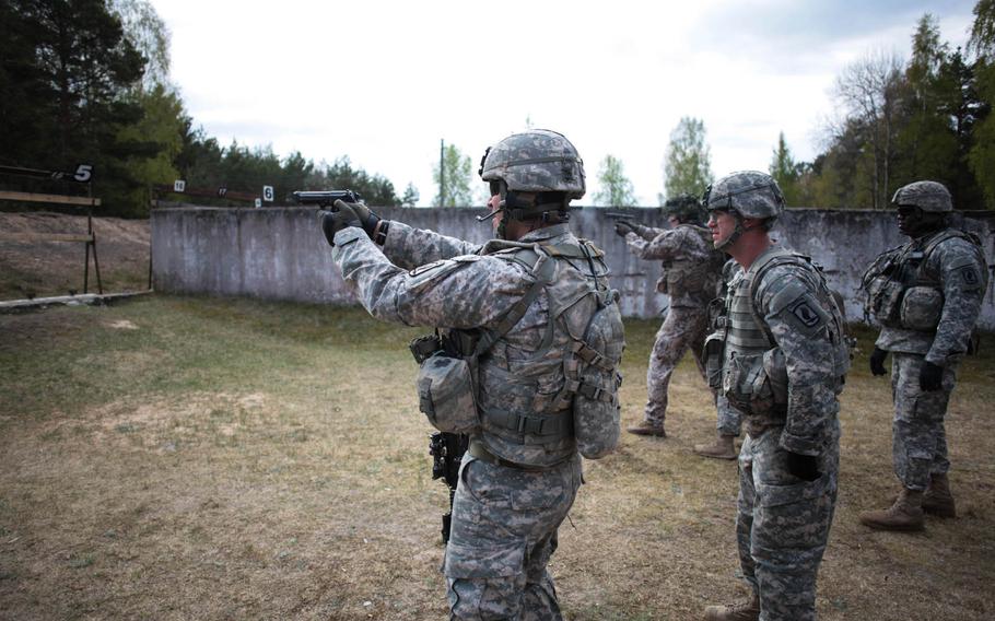 An American and a Latvian soldier fire pistols Wednesday, April 30, 2014, as part of a stress firing exercise that also helped build camaraderie between the two forces, which could end up training together for months as the U.S. seeks to reassure NATO allies that are nervous that Russia's aggression in Ukraine could spill over.