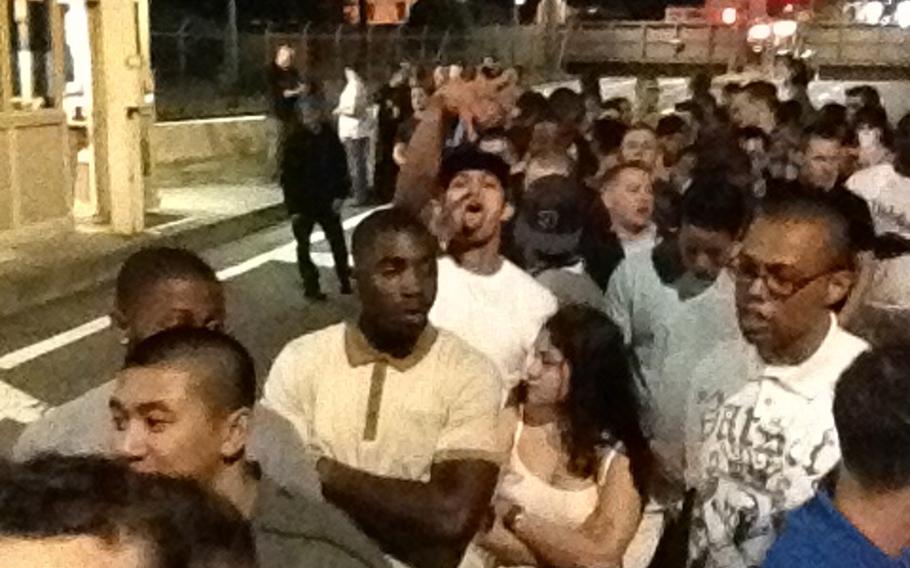 More than 200 active-duty servicemembers wait at the entrance to Yokota Air Base, Japan, early Saturday morning, May 17, 2014, after a night out on the town. Base officials conducted a mass drug-testing of 273 troops.