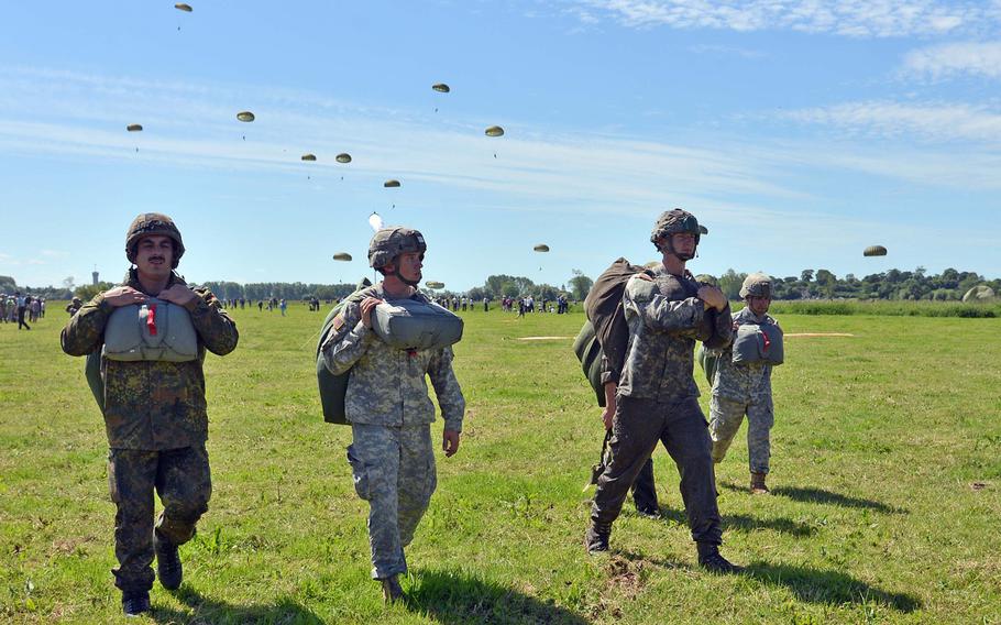German and American paratroops walk to a meeting point after parachuting in to La Fiere drop zone in a 70th anniversary of D-Day commemoration near Cauquigny, France, Sunday, June 8, 2014. More than 600 paratroops from several nations participated in the drop.