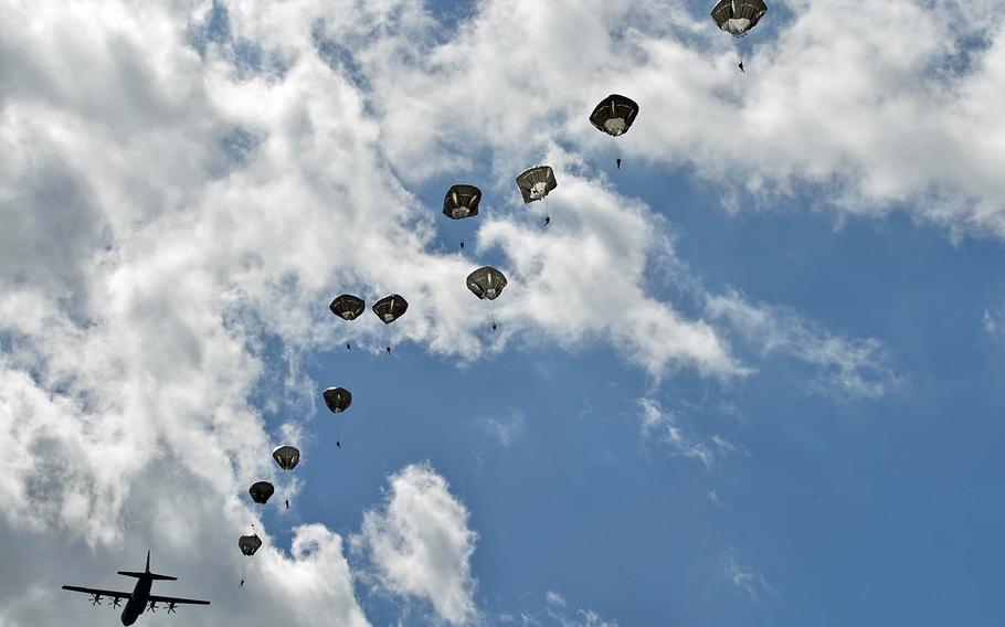 A string of paratroops floats down to earth after jumping from a C-130 airplane during a 70th anniversary of D-Day commemoration near Cauquigny, France, Sunday, June 8, 2014. More than 600 troops, including more than 400 Americans, landed at La Fiere drop zone, marking the World War II battle there in 1944.
