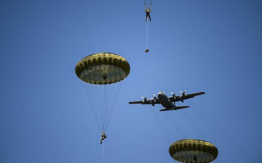 A C-130 flies over paratroops before dropping its own troops in Cauquigny, France, on Sunday, June 8, 2014. The drop was held to commemorate the 70th anniversary of D-Day.
                