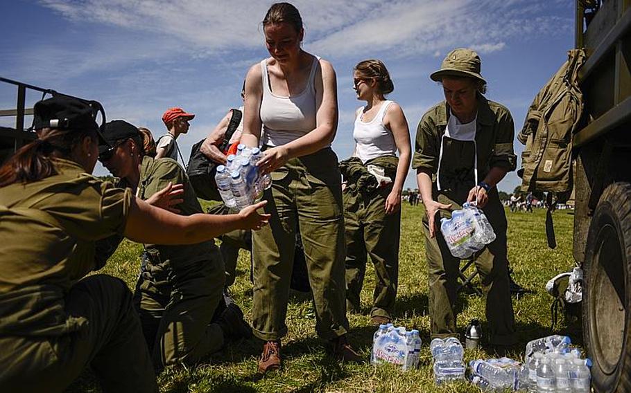 Re-enactors distribute water in Cauquigny, France, during a parachute drop commemorating the 70th anniversary of D-Day, Sunday, June 8, 2014.
                