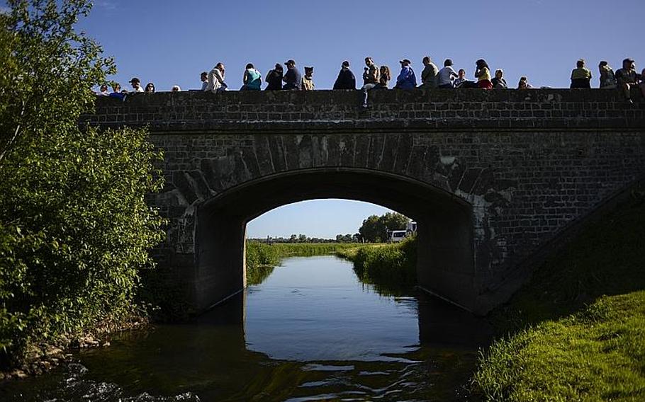 Spectators sit along a bridge in Cauquigny, France, to watch a parachute drop commemorating the 70th anniversary of D-Day, Sunday, June 8, 2014.
                