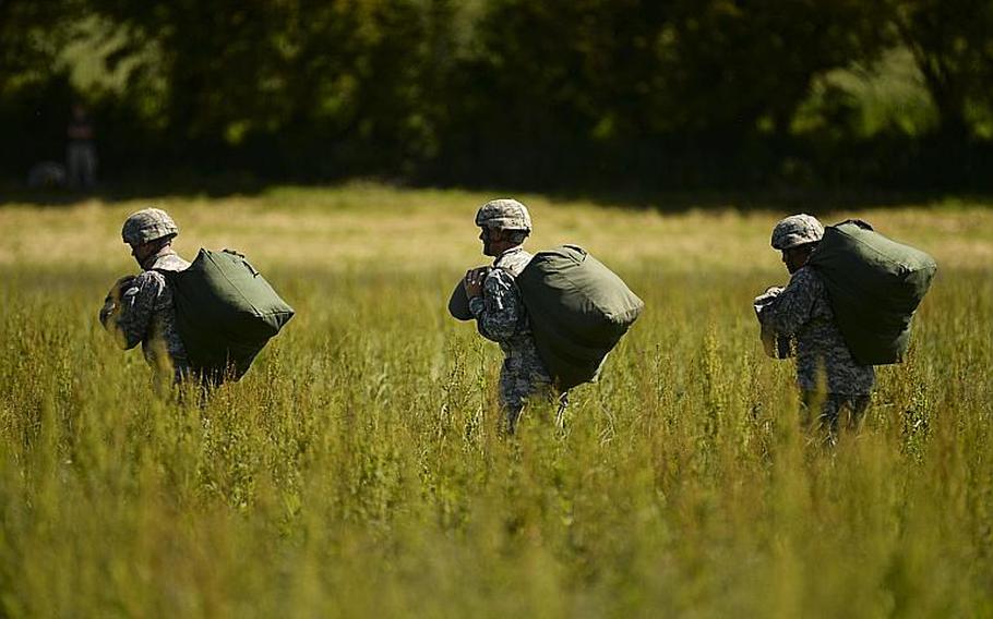 Airborne soldiers head to the meeting point after jumping in Cauquigny, France, to commemorate the 70th anniversary of D-Day, Sunday, June 8, 2014.
                