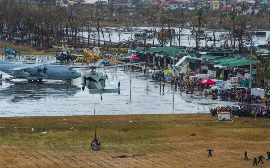 An MH-60S Sea Hawk helicopter from the Island Knights of Helicopter Sea Combat Squadron 25 drops supplies onto Tacloban Air Base in support of Operation Damayan in November 2013 in the days after the island was hit by Typhoon Haiyan.