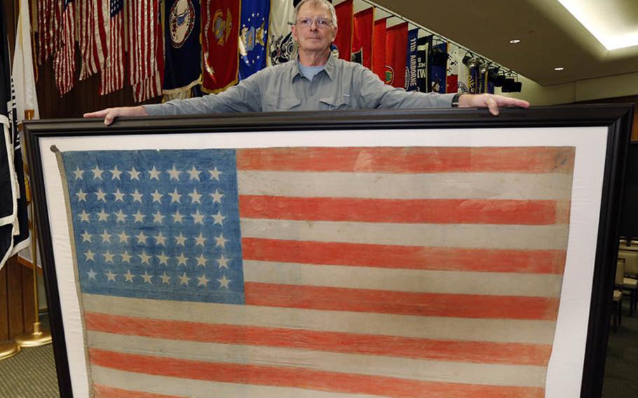 Jerry Landrum poses with the Omori flag at its current home at the Virginia War Memorial in Richmond.