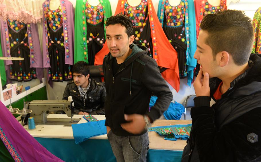 Khaled Qadis, center, discusses the drop in business at his family's dress shop in Kabul, Afghanistan. Last year saw a 50 percent drop in business over 2013, he said.