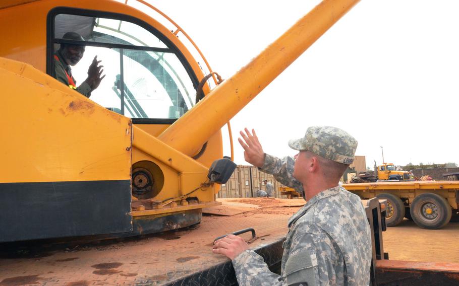Cpl. James Lembke, a West Seneca, N.Y., native and a heavy equipment operator for the Headquarters and Headquarters Company, 62nd Battalion, 36th Engineer Brigade, tells a Liberian worker to load four containers onto the non-tactical vehicles headed to the staging area in Buchanan, in support of Operation United Assistance, Joint Forces Command ? United Assistance, at the National Police Training Academy, Paynesville, Liberia.