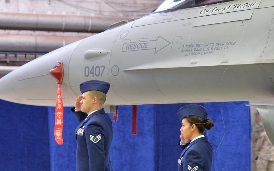 Staff Sgt. Juan Silver, left, and Senior Airman Kimberly Szydlowski salute after unveiling Col. Joseph McFall's name on a 52nd Fighter Wing F-16 during an assumption of command ceremony at Spangdahlem Air Base, Germany, Thursday, Feb. 5, 2015. McFall took command of the wing at the ceremony.