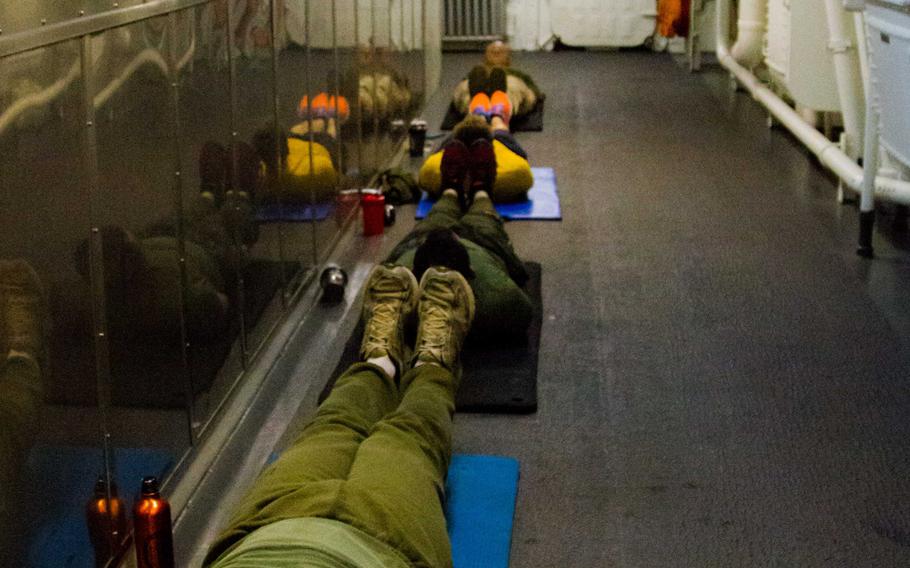 Marines and sailors conduct an evening workout session in a passageway aboard the amphibious transport dock ship USS New York, Feb 28, 2015.