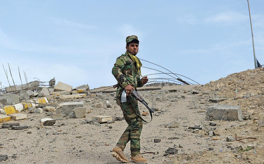 A Shiite militiaman from the Badr Organization walks to the end of a bridge destroyed by Iraqi forces near Jurf al-Nasr in an October 2014 operation, March 8, 2015. The bridge had previously been used to ferry supplies to Islamic State fighters in the town.