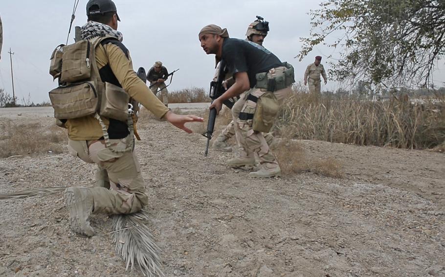Iraqi army soldiers duck as an Islamic State sniper's first volley cracks overhead in Karmah, Iraq, March 12, 2015. His battalion, part of the Iraqi 6th Division, is fighting to keep the militants out of rocket range of Baghdad.