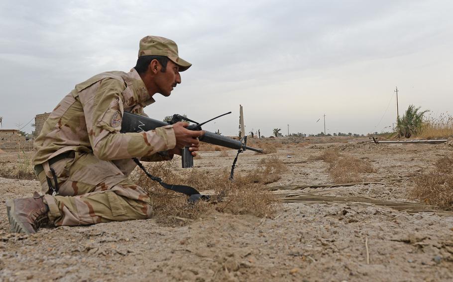 An Iraqi soldier ducks down and speaks on his radio as Islamic State sniper fire cracks overhead in Karmah, Iraq, March 12, 2015.