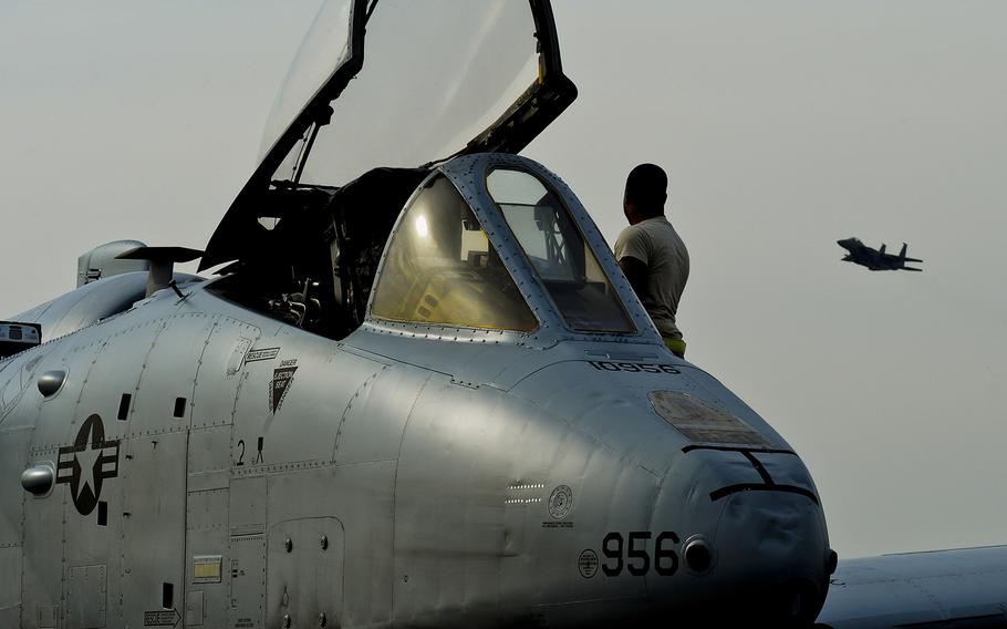 An A-10C Thunderbolt II sits on the flight line as an F-15E Strike Eagle flies over at RAF Lakenheath, England, on March 13, 2015. The A-10s and airmen are deployed out of Davis-Monthan Air Force Base, Ariz., as part of Operation Atlantic Resolve.