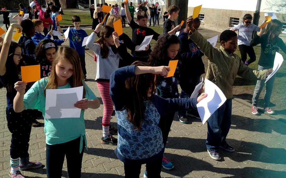 Fourth-graders at Boeblingen Elementary and Middle School in Stuttgart, Germany, position sheets of paper to capture the reflection of the sun being eclipsed by the moon on Friday morning, March 20, 2015. Students without protective glasses used alternative means to catch a glimpse of the eclipse.