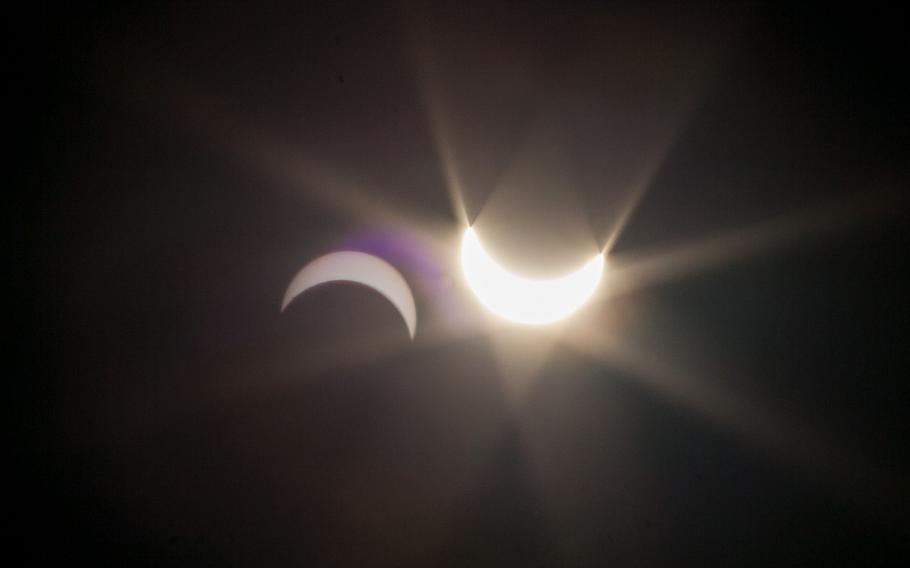 Internal reflections in a camera lens create an inverted image of the Friday, March 20, 2015, partial eclipse of the sun next to an image of the actual eclipse, right.