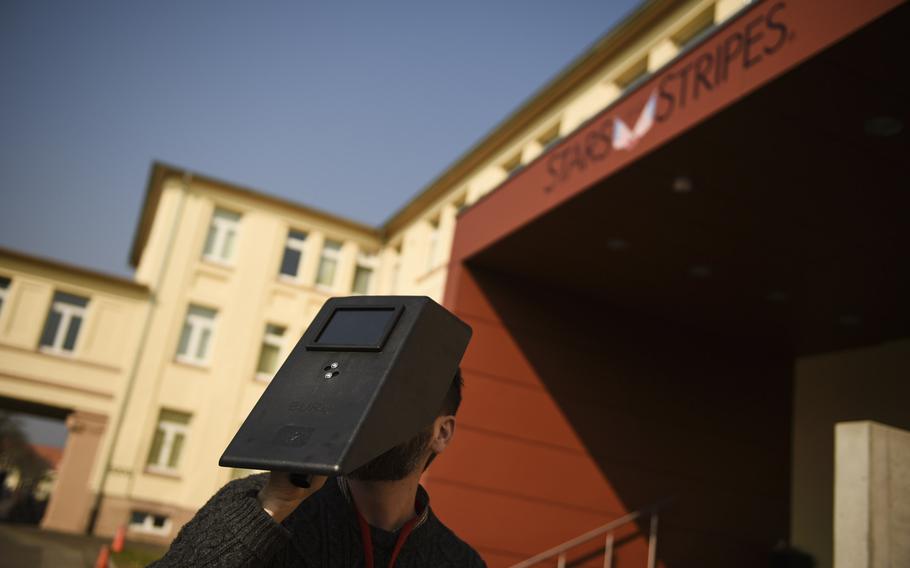 Stars and Stripes employee Shane Schiermeier looks at the partial solar eclipse through a welding mask, Friday, March 20, 2015 on Kleber Kaserne, in Kaisersluatern, Germany.