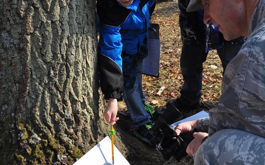 Air Force Lt. Col. Jason Lamont projects the image of Friday's partial solar eclipse onto a poster board through a pair of binoculars. Looking on are Evan Rotramel, left, and Marshall Lamont. Evan and Marshall spent the morning of March 20, 2015, at the base pond on Ramstein Air Base, Germany, with their Ramstein Elementary School second-grade class, exploring nature and viewing the partial solar eclipse.