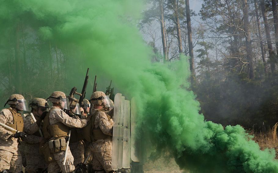 Smoke grenades thrown by course instructors envelop Marines with 2nd Battalion, 6th Marine Regiment, in thick, green smoke during a nonlethal weapons training exercise aboard Camp Lejeune, N.C., on March 25, 2015.