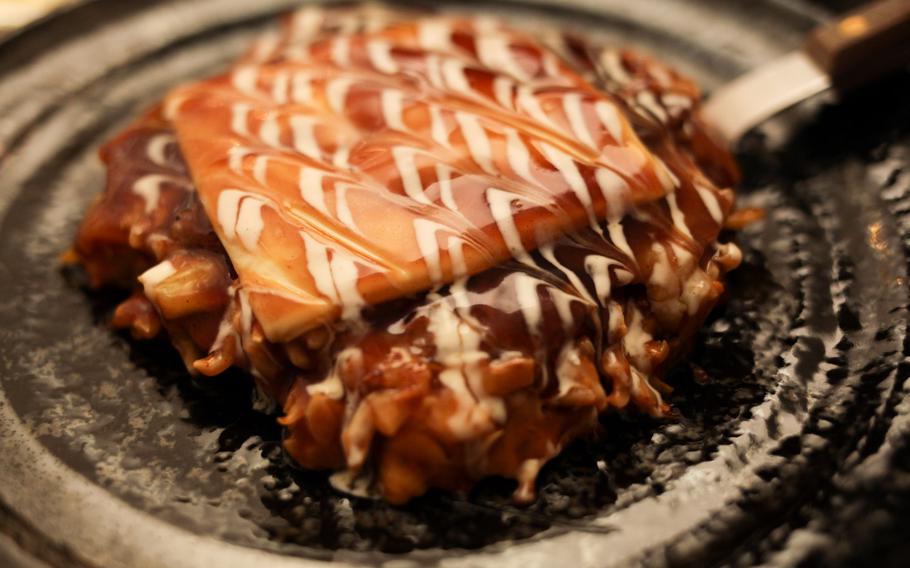 A plate of okonomiyaki, a type of savory Japanese pancake, with pork, kimchi and cheese, is an out-of-the-ordinary choice at Ayame Japanese restaurant in Kaiserslautern.