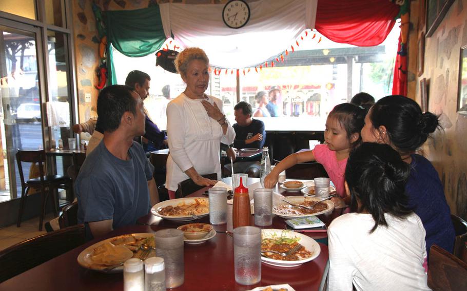 One of the owners of Azteca chats with a family as they finish their meal at the Mexican restaurant in Honolulu.