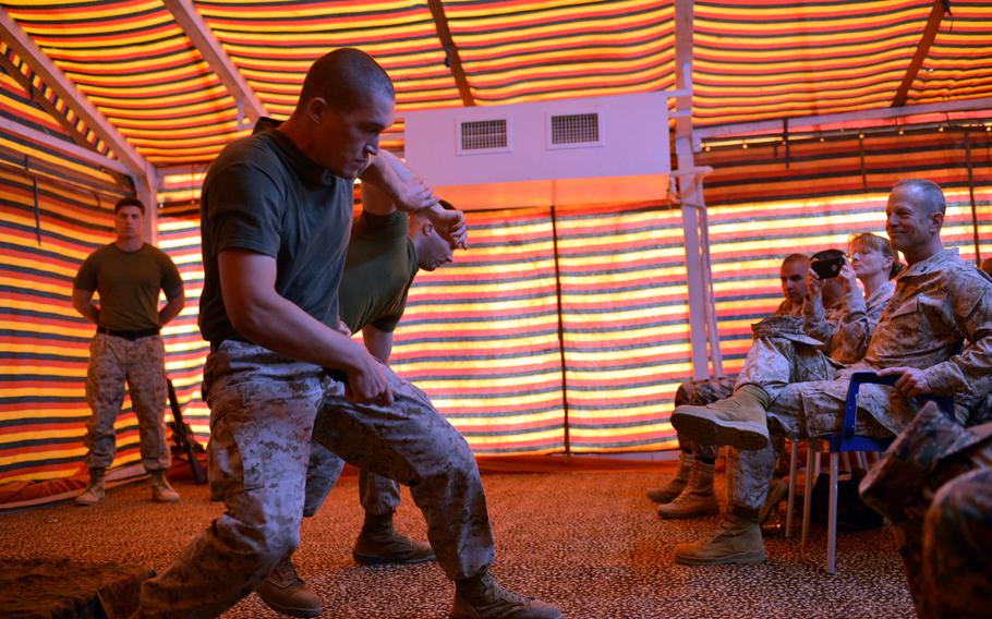 Marine Corps martial arts instructor Sgt. Bruce Sutherland, foreground, demonstrates a maneuver to strip a handgun from an adversary, played by fellow instructor Sgt. Bryan Tate, during a display for Marine and Jordanian forces at Camp Titin, Jordan, during the exercise Eager Lion in May 2015. Marine Maj. Gen. Burke Whitman, one of the exercise leaders, looks on from the right.