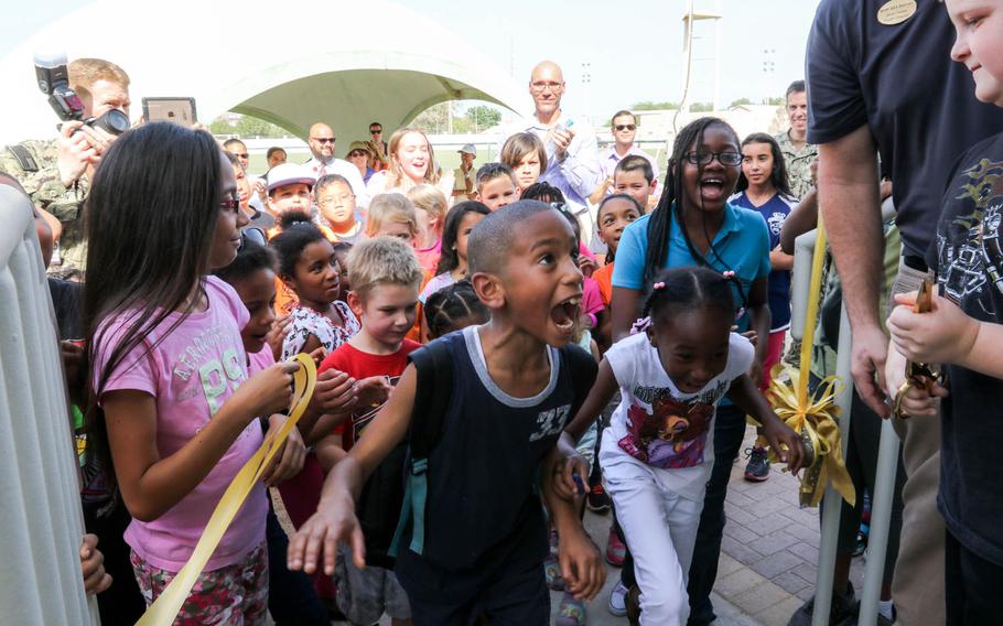 Children, of U.S. personnel stationed at Naval Support Activity Bahrain, charge into a new $480,000 school age care facility, immediately following the ribbon cutting ceremony June 2, 2014. The facility has the capacity to support 75 Kindergarten through 6th grade kids, to accommodate a growing population of dependents.