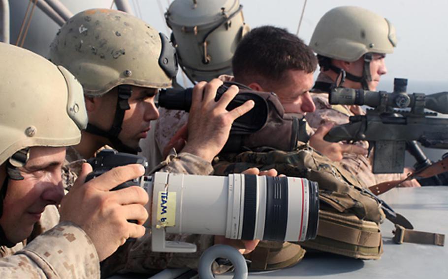 In this image taken by combat camera personnel, U.S. Marine Corps snipers provide cover and observation during a boarding and seizure operation to recover the Magellan Star from suspected pirates who took control of the ship in the Gulf of Aden on Sept. 9, 2010. Combat camera troops get training in aerial, underwater, night-vision and low-light photography and videography
                