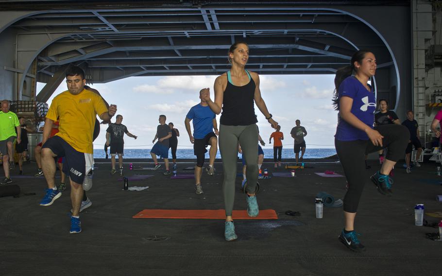 Sailors aboard the USS George Washington participate in a total body fitness class in the hangar bay of the aircraft carrier on May 21, 2015. After some 5,000 sailors failed their PT test last year, the Navy is retooling of its fitness program to includes making gyms available for longer hours and performing fitness ?spot checks? between testing cycles.