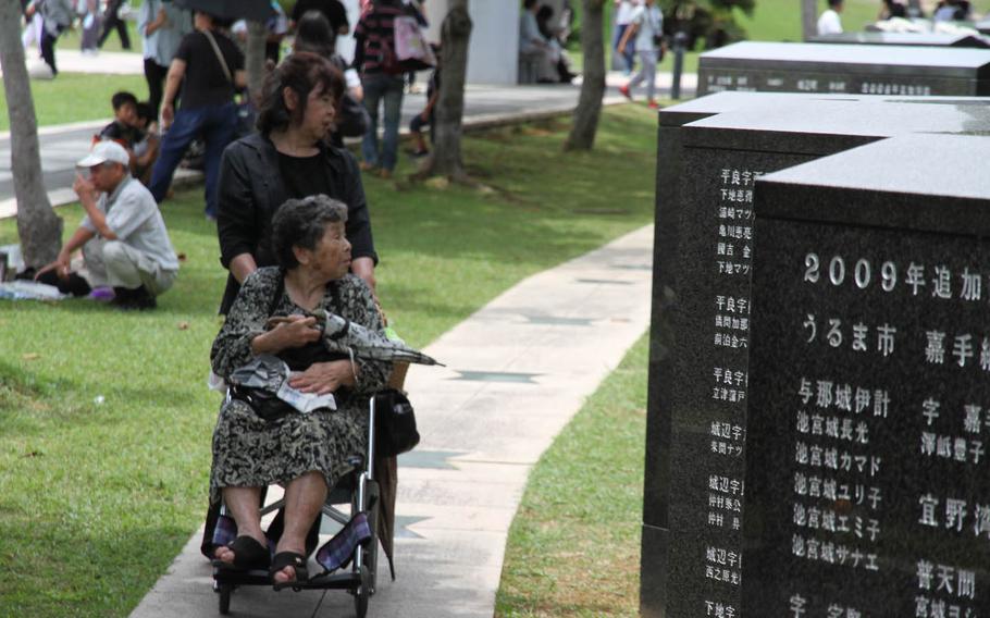 An elderly Okinawan woman attempts to find a lost loved one's name on the memorial stone Tuesday at Okinawa Peace Memorial Park. 