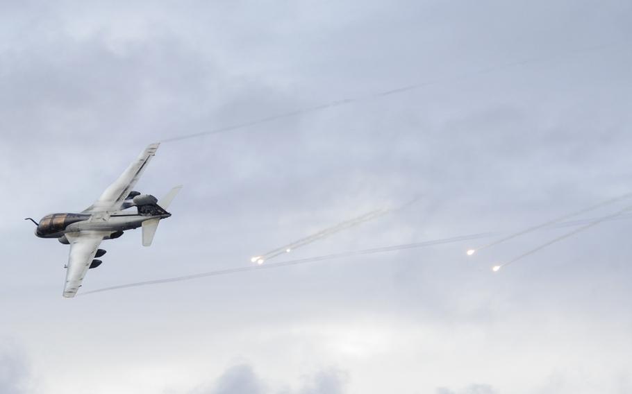 An EA-6B Prowler, assigned to the ''Gray Wolves'' of Electronic Attack Squadron 142, shoots flares as it passes the aircraft carrier USS Nimitz during an airshow performed by the squadrons of Carrier Air Wing 11 on December 7, 2013.