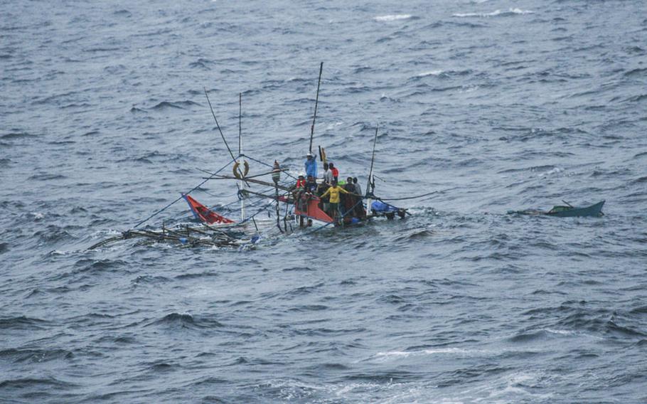Stranded Filipino fishermen await rescue from their sinking fishing vessel by the USNS Impeccable in the South China Sea on July 19, 2015.